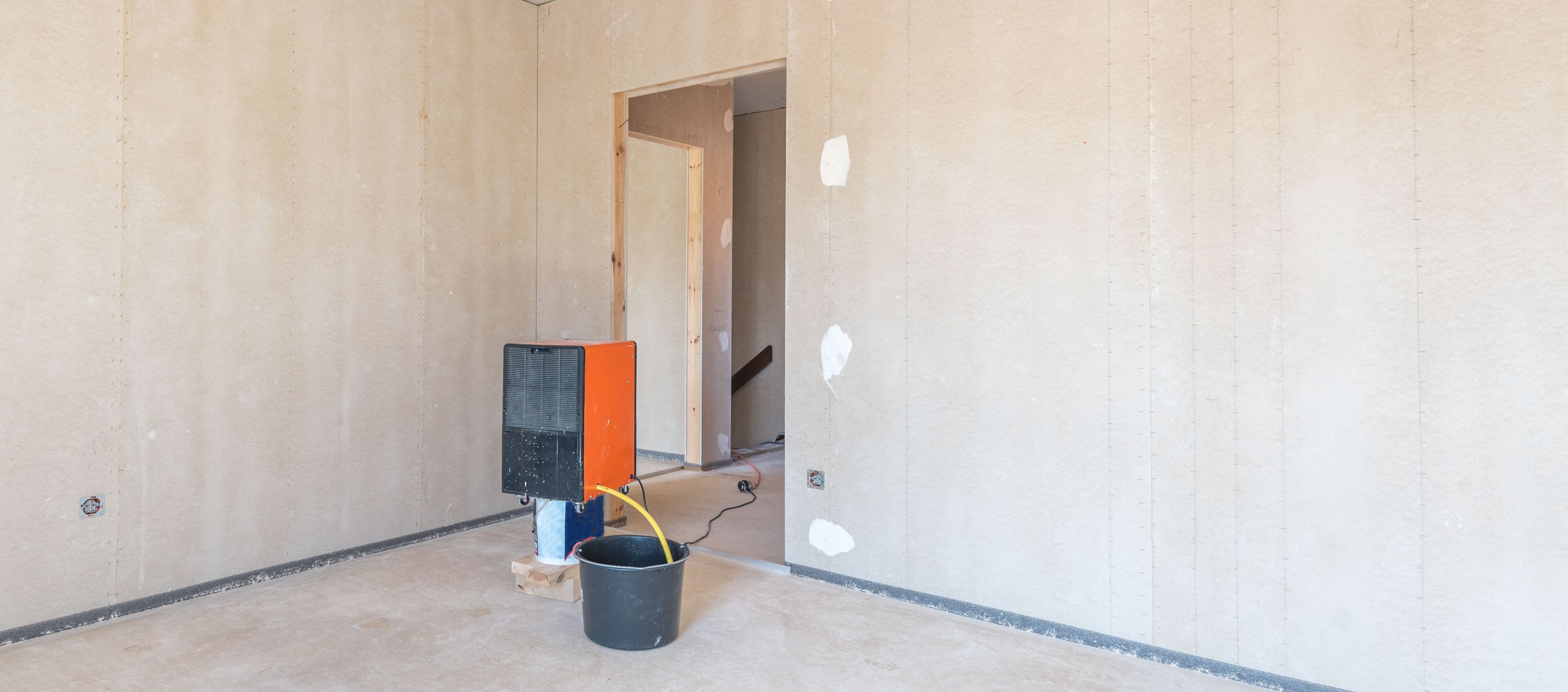 Eine Bautrocknung im Rahmen eines Neubaus. Zu sehen ist ein Bautrockner in einem Rohbau.
